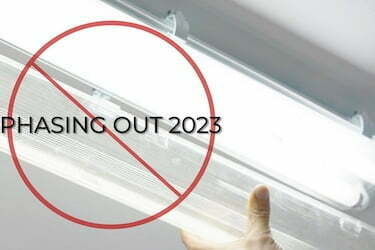 Image featuring an electrician opening a fluorescent twin tube lamp, with a message that fluorescent tubes are phased out in 2023.
